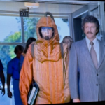 A scene from the boy in the plastic bubble where Todd is walking into school with his father. He is wearing what looks like a space suit.