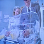 Picture from the boy in the plastic bubble of the parents looking at the baby in the incubator.